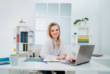 Resepsiyon masasının arkasında cana yakın sekreter kadın var.