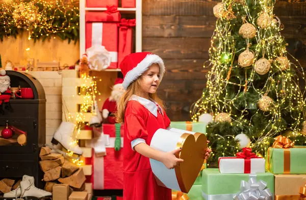 Noel hediyesi tutan komik çocuk. Yetenekli çocuk. Model çocuk hediyeyle eğleniyor. Çocuklar içeride Noel ağacının yanında eğleniyorlar. Noel çocukları. Mutlu Noeller dilerim.