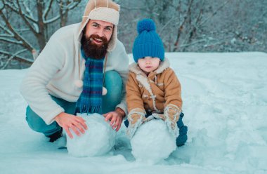 Kardan adam yapan mutlu baba ve oğul. El yapımı komik kardan adam. Mutlu aile için en iyi kış oyunu. Noel tatili. Güneşli kış gününde gülümseyen mutlu bir aile. Babalar Günü