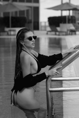 Beautiful young woman in a swimming pool, hot summer. Beautiful women relaxing at the luxury poolside. Female at travel spa resort pool. Summer luxury vacation