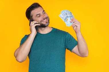 Sarı stüdyoda nakit para tutan zengin bir adam. Büyük şans, afiş. Dolar nakit para konsepti. Nakit para kazanmak için sevinir, şanslı para. Nakit parası olan bir adam. Finansal şans ve başarı