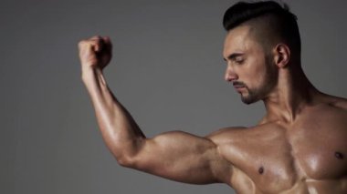 Kaslı seksi adam kaslarını esnetiyor. Erkek sporcu, kaslarını esneten sporcu, kas kaslarına bakıyor. Erkek kas pazısı kolu. El, kol bisepsi, yakın plan. Güçlü, seksi ve üstsüz erkek model.