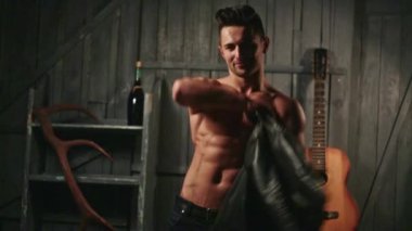 Üstsüz adam soyundu. Kaslı vücutlu genç seksi adam gömleğini çıkarıyor. Seksi erkek model. Baştan çıkarıcı adam. Yakışıklı üstsüz adam. Kaslı erkek vücudu fit. Erkek model.
