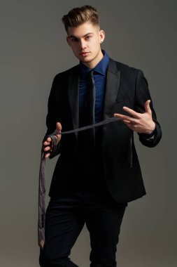 Adam kravat bağlıyor. Resmi erkek giyimi. Smokin ya da resmi takım elbise için Boyunbağı. Kravatlar ve fiyonklar. İş adamı kostümü. Kravatlı bir erkek model. Klas takım elbiseli genç adam kravat ayarlıyor. Moda görünüşü.