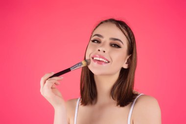 Woman applying foundation powder or blush with makeup brush. Facial treatment, perfect skin, natural make up, facial beauty. Isolated on studio background. Applying makeup clipart