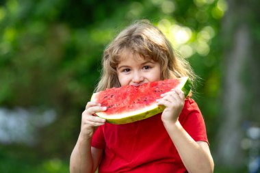 Karpuzlu şirin çocuk. Yazlık parkta karpuz yiyen komik çocuk. Çocuk, bebek, sağlıklı yemek. Bahçede karpuz yiyen bir çocuk. Çocuklar dışarıda meyve yer. Çocuk karpuz seviyor.