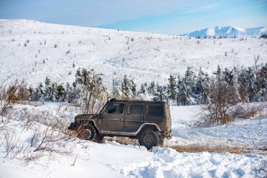 Kışın dağlarda bir cip. Kış karında off-road aracı. Kış ormanlarında yol dışı araç, karda sürüklenmek. Kar fırtınasında bir SUV. Arabalar off-road yollarında, kış off-road pistlerinde