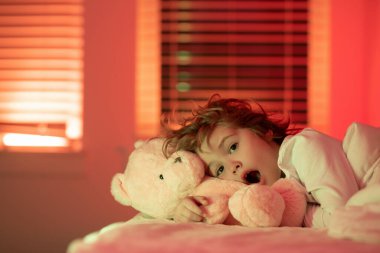 Yatakta korkmuş bir çocuk. Çocuklar için bir kabus. Büyük yatakta yatan küçük bir çocuğun portresi. Mutlu çocuklar iyi geceler diliyor. Çocuk yatakta uykulu.