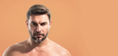 Yüz kreminden sonra yarı çıplak genç bir adamın güzellik portresini kapat. Çekici esmer adam tenine dokunuyor. Sakallı ve modern saç kesimli erkek modeller. Başlık için pankart, kopyalama alanı