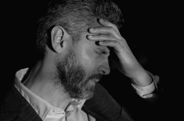 Yorgun adam acı çekiyor. Stresli bir adamın portresi ofiste baş ağrısından muzdarip. Stresli bir iş. Ağrılı bir adamın ağrıdan dolayı migreni tutar. Stresli, baş ağrısından yorgun bir adam.