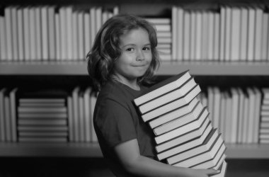 Kitabı olan bir öğrenci. Öğrenci çocuk kütüphanede kitap okuyor. Çocuklar okumayı öğrenir. Öğrenci kütüphanede kitap okuyor. Ödev yapan okul çocuğu, sınıfta sıkı çalış.