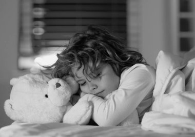 İyi uykular. Çocuk oyuncak ayıyla uyur, uyur. Çocuk yatakta uyuyor.