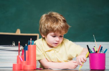 Komik küçük çocuk tahta arka plan üzerinde eğleniyor. Okul bahçesindeki ilkokuldan bir çocuk öğrenci. Çocuk okulu. Çocuk okulu. Eğitim süreci