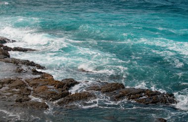 Denizde kayaların üzerine dalgalar sıçrıyor. Dalga okyanustaki taşa bir tüp ile vurdu.