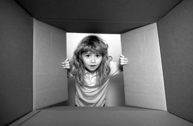 Komik çocuk hediyeyi açıyor ve karton kutunun içine bakıyor. Çocuklar şaşırmış yüz ifadeleri