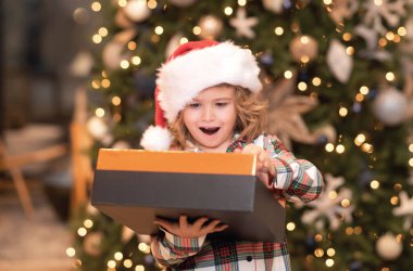 Sürpriz çocuk Noel hediyelerini açıyor. Noel 'de evde bir çocuk. Noel 'i ya da yeni yılı kutlayan küçük bir çocuk. Kapalı portre, komik çocuk yüzü.