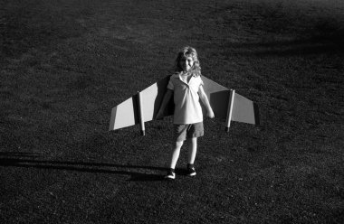 Beyaz çocuk çimenli yaz tepesinde arka planda oyuncak uçakla oynuyor. Mutlu gelecek konseptini hayal ediyorum.