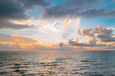 Deniz batımında bulutlu gökyüzü, okyanus sahilinde gün doğumu. Gün batımından sonra gökyüzünde gün batımı manzarası. Gökyüzüne ve denize karşı farklı renkte bulutlarla gün doğumu