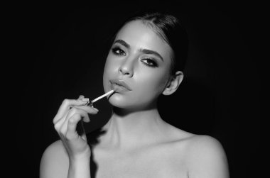 Studio portrait of beautiful woman with red lipstick. Beautiful young woman applying lipstick on her lips, isolated on studio background