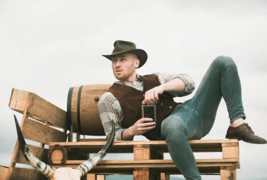 Şapkalı bir kovboy. Viski ya da brendi ile çekici bir adam. Batı hayatı. Yakışıklı sakallı batı çiftçisi. Kovboy ya da çiftçi portresi. Batı