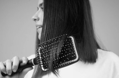 Close up young beautiful woman combing brown hair. Hair Care. Beautiful brunette woman hairbrushing hair with hairbrush. Brushing healthy hair with comb clipart