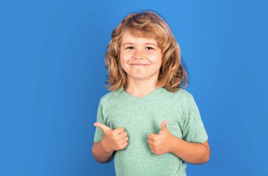 Child showing thumbs up on studio isolated background. Portrait of kid boy making thumbs up sign