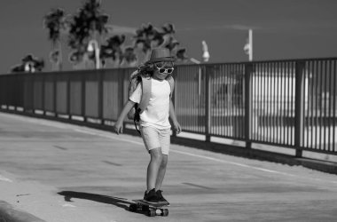 Kaykayla kayan çocuk. Çocuk kaykaycı sokakta kaykaya biniyor. Yaz şehrinde bir çocuk. Küçük bir çocuk, parkta ilk kez kaykay süren küçük bir çocuk, kaykay yapmaya çalışıyor.