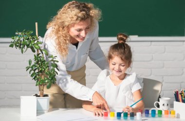 School girl drawing with teacher. Children from elementary school study at draw lesson. Pupil girl with teacher painting at art school