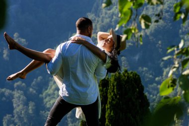 Adam kadını güvenli bir şekilde kollarında tutuyor. Kaygısız ve derinden aşık olan çift, birbirlerine eşlik etmekten hoşlanıyordu. Yaz doğasına aşık romantik çift. Onu zahmetsizce taşıyor.