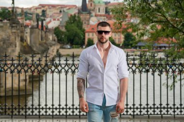 Seksi yakışıklı adamın portresi. Hippi adam dışarıda modellik yapıyor. Şehirde güneş gözlüklü genç bir moda adamı. Kendine güvenen erkek model. Adam gururlu görünüyor. Avrupa caddesinde çekici bir adam. Zarif adam.