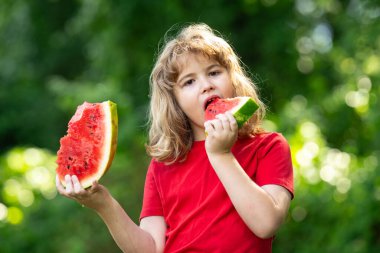 Kid 'in karpuzlu yaz portresi. Yaz parkında karpuz yiyen tatlı sarışın çocuk. Bahçede karpuz yiyen bir çocuk. Çocuklar dışarıda meyve yer. Çocuk karpuz seviyor.