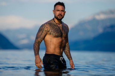 Kaslı adam gölde suda rahatlıyor. Deniz suyunda seksi erkek modeli. Yakışıklı çocuk Alps gölü suyunda dinleniyor. Seksi, ıslak erkek gövdesi, damlalık suda. İnsan özgürlüğü yaşam tarzı. Güçlü kaslı adam.