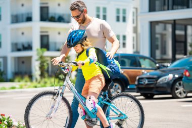 Baba oğul bisiklet sürmeyi öğreniyor ve Babalar Günü 'nde birlikte eğleniyorlar. Baba, Amerikan mahallesinde oğluna bisiklet sürmeyi öğretiyor. Baba oğul kavramı. Baba destekçisi oğul