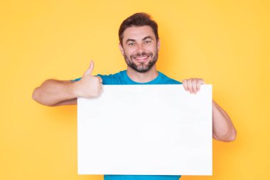 Yakışıklı adam stüdyo arka planında boş tahtayı tutuyor. Kopyalama alanı olan boş tabela gösteren bir adam. Fikir ve teklif. Reklamınız. Metin ve maket için boş alanı olan boş tahta