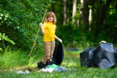Çocuk çöp toplamaya yardım ediyor. Kirli orman. Çöp yığını. Gezegen kirliliği çevre koruma kavramı. Ormanı temizliyorum. Çöp torbalarına çöp koyan çocuk, çevre koruması