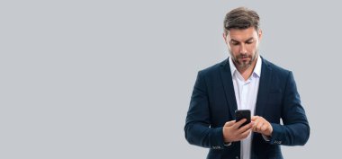 Takım elbiseli adam stüdyo arka planında izole edilmiş cep telefonu kullanıyor. Cep telefonu kullanan orta yaşlı bir adamın portresi. Akıllı telefonu olan adam stüdyo geçmişini izole etmiş. Banner, boşluğu kopyala