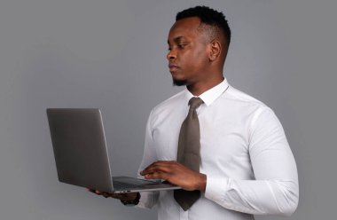 Genç işadamı dizüstü bilgisayar kullanıyor ve modern ofiste çalışırken notlar alıyor..