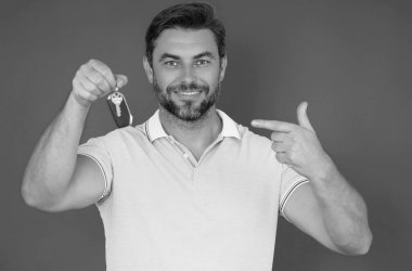 Anahtarı olan bir iş adamı. Emlakçıda anahtarlar sarı renkte tutuluyor. Emlakçıda anahtarlar var. Simsar ya da anahtarı olan bir emlakçı. Tişört giyen iş adamı. Araba anahtarı ya da ev anahtarı