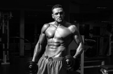 Spor salonundaki adam. Kaslı ve güçlü adam egzersiz yapıyor. Sporcu ağırlıklarla egzersiz yapıyor. Fitness ve Crossfit