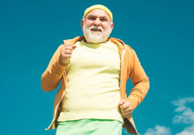 Yaşlı adam mavi gökyüzü arka plan üzerinde spor pratik. Yaşlı adam koşuyor. Altın çağ dedesi. Üst düzey fitness kişi iyi sağlık için parkta çalışan. Yaz ve hareketli tatiller