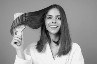 Young woman combing hair. Beautiful woman brush healthy hairs. Hairstyle and haircare concept. Girl combing and brushing hair in studio. Woman with comb combing hair. Hair brush