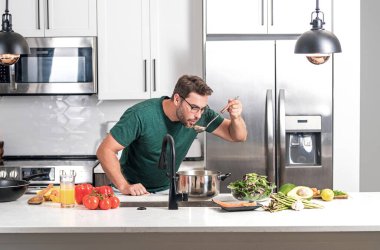 Aşçı adam mutfakta tencerede yemek pişiriyor. Gurme yemeği hazırlama süreci. Adam evde yemek pişiriyor, esrar kullanıyor. Şef yemek pişiriyor. Yakışıklı aşçı aşçı konsepti