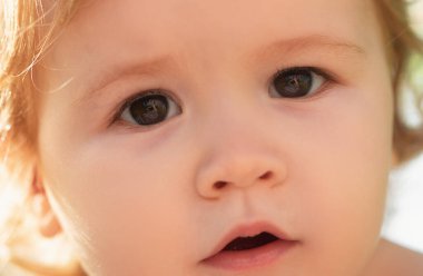 Kırpılmış yüzlü, küçük sarışın bir erkek bebeğin yakın portresi. Komik çocuk suratı