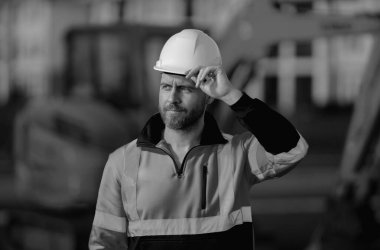 Endüstriyel alanda kazıcılı inşaat işçisi. Kasklı, buldozerli bir işçi. Mühendis, inşaat firmasında çalışıyor. Kazı ustabaşı ve traktör. Kazıcılı işçi