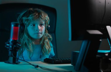 Çocuk geceleri çevrimiçi öğreniyor, evdeki oturma odasında masaüstü bilgisayarını kullanıyor. Evde bilgisayar teknolojisi kullanan bir çocuk