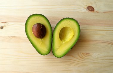 Ahşap arka planda avokado. Avokado meyvesi. Çiğ meyveler sağlıklı yeşil yiyecekler. Yarım avokado.