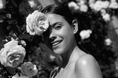 Woman enjoying a day in the park on summer. Lifestyle and wellness. Beautiful natural woman in the garden of roses. Sexy woman enjoying flowers over spring garden background. Rose spring garden