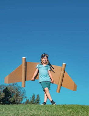 Child boy playing with cardboard toy airplane wings craft in sky with copy space for text. Creative with family and dreaming of flying concept. Travel and imagination concept