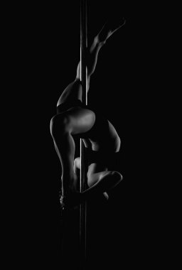 Esnek kız gerilmek için pilon üzerinde jimnastik yapıyor. Güzel, seksi, esnek kadın seksi, esnek bir vücut gösteriyor. Esneklik siyahta geriliyor. Esnek kadın vücudu. Direk dansı
