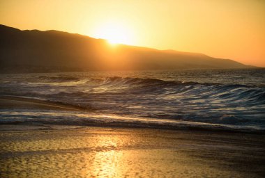 Deniz yüzeyinin altında büyük sarı güneşli bir gün batımı. Sakin okyanus, gün batımında gökyüzü ve bulutların arasında güneş. Sakin okyanus ve gökyüzü arka planı. Cennet plajı